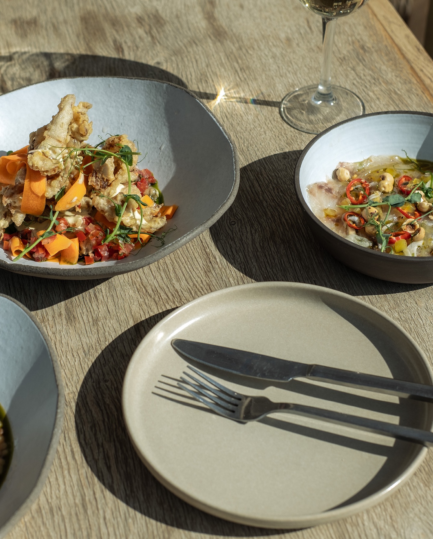 Sunlit table with plates and wine