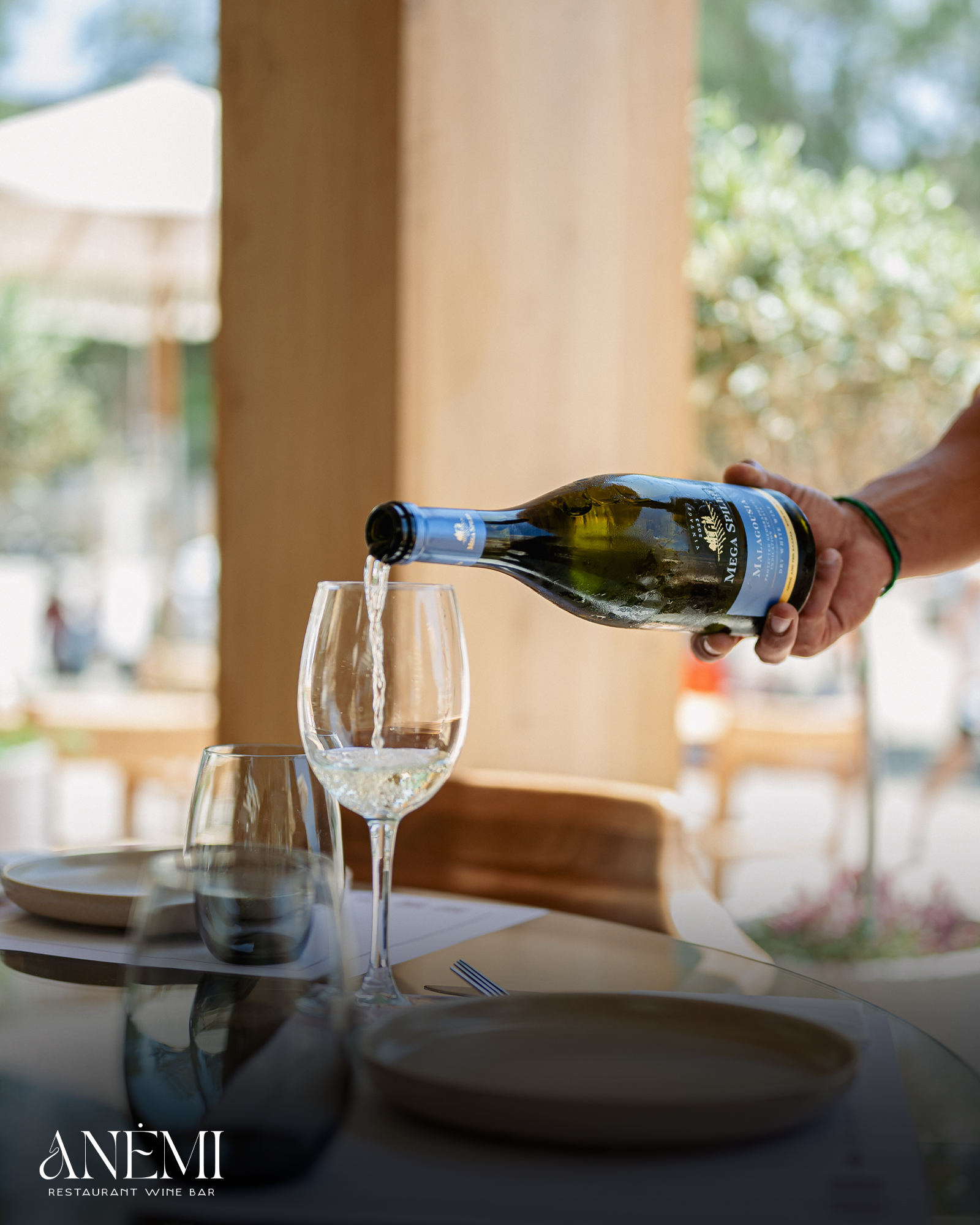 White wine poured at a sunlit Anemi table